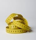 A close-up image of a coiled yellow measuring tape displaying numbers clearly.